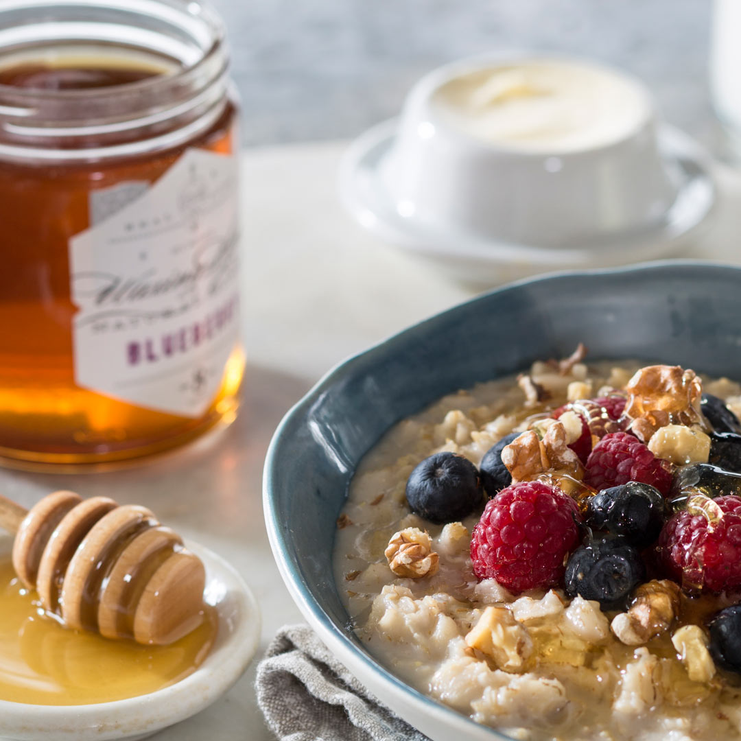 Oatmeal topped with honey, blueberries, and raspberries 