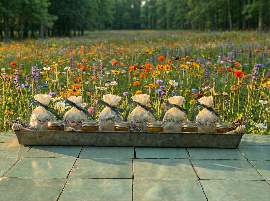 bags of honey party favors on a metal tray with a field of wildflowers in the background