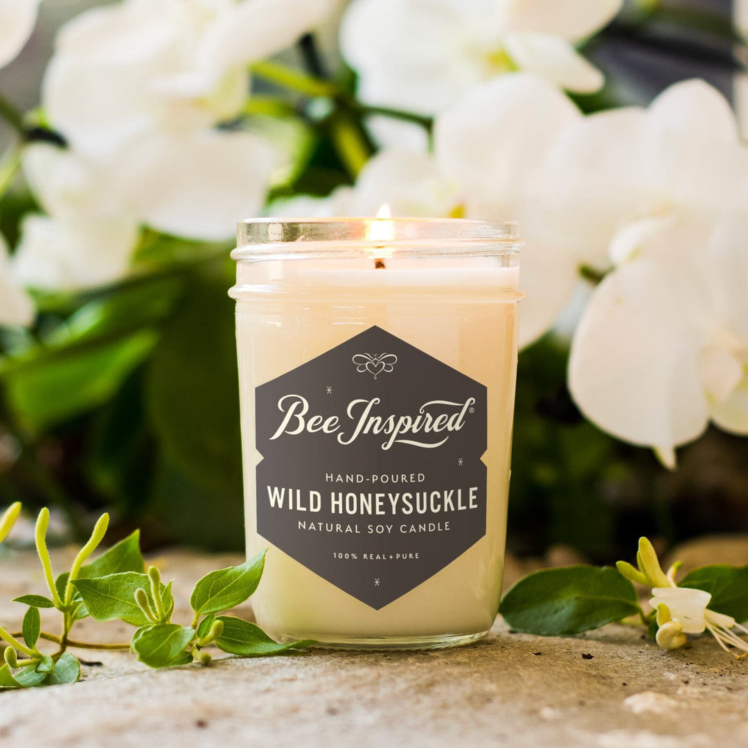 Wild Honeysuckle jelly jar candle burning in front of white flowers 
