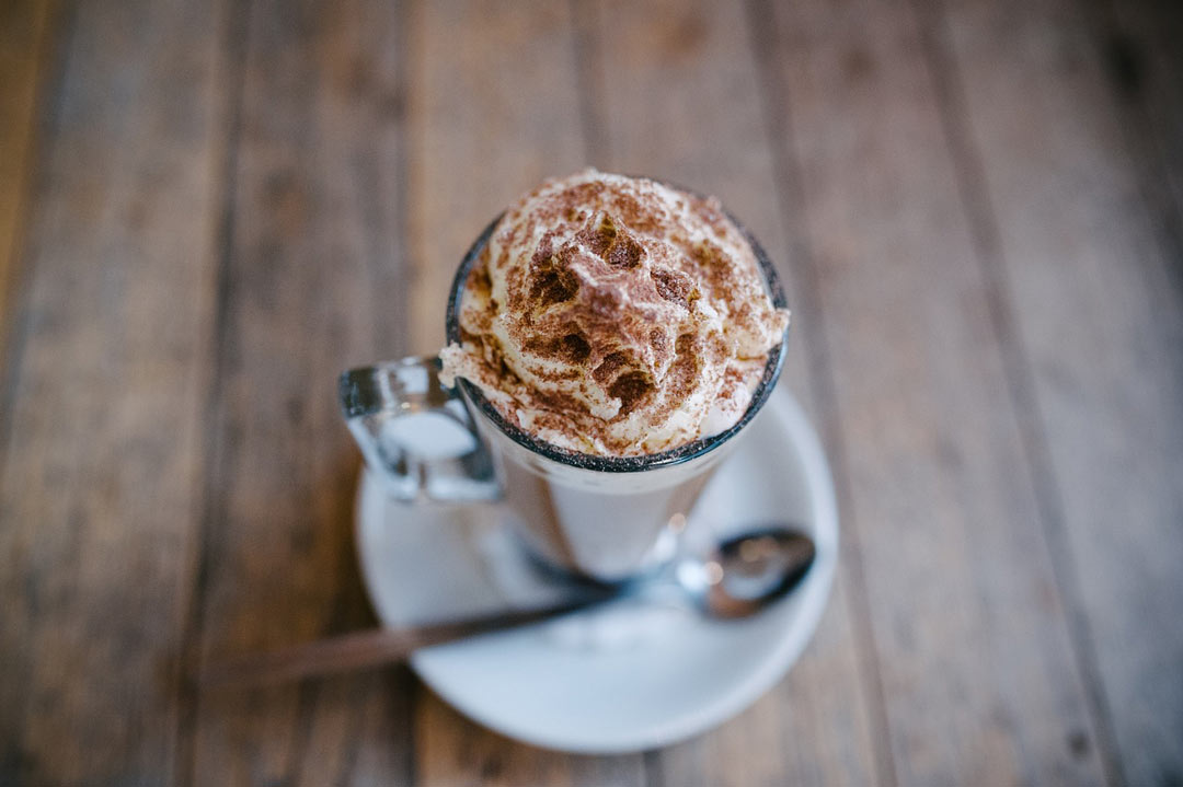 Aerial view of glass of hot chocolate topped with whipped cream on wooden table 