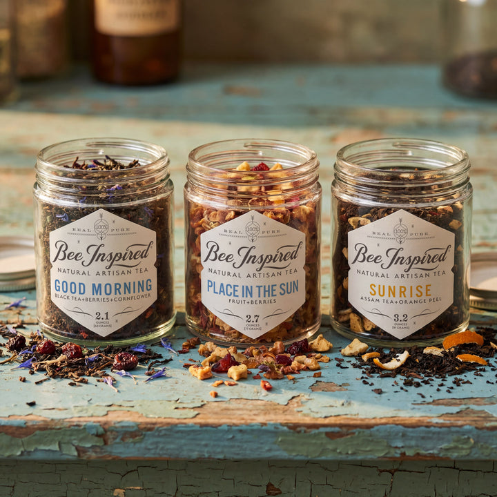 Three jars of 'Bee Inspired' tea on a rustic wooden surface