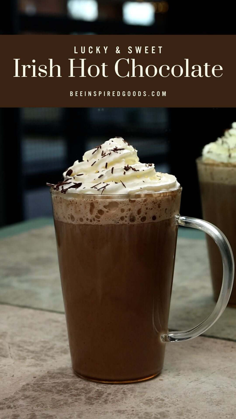 "Lucky & Sweet Irish Hot Chocolate beeinspiredgoods.com" with a clear mug of hot chocolate topped with whipped cream and shaved cocoa