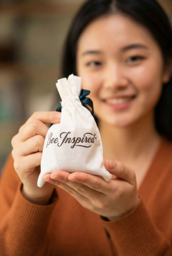 Woman holding a white drawstring bag with 'Bee Inspired' text.