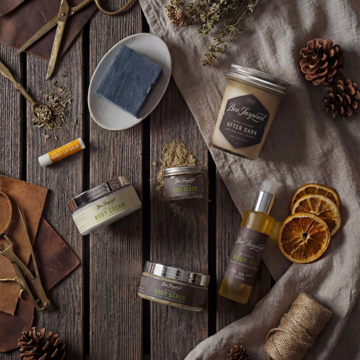 Collection of natural skincare products on a wooden surface with dried oranges and pine cones.