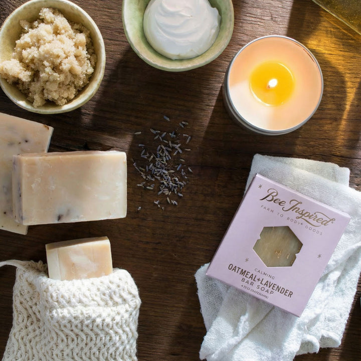 Bee Inspired oatmeal-lavender bar soap with candle, soap bars, and lavender on a wooden surface