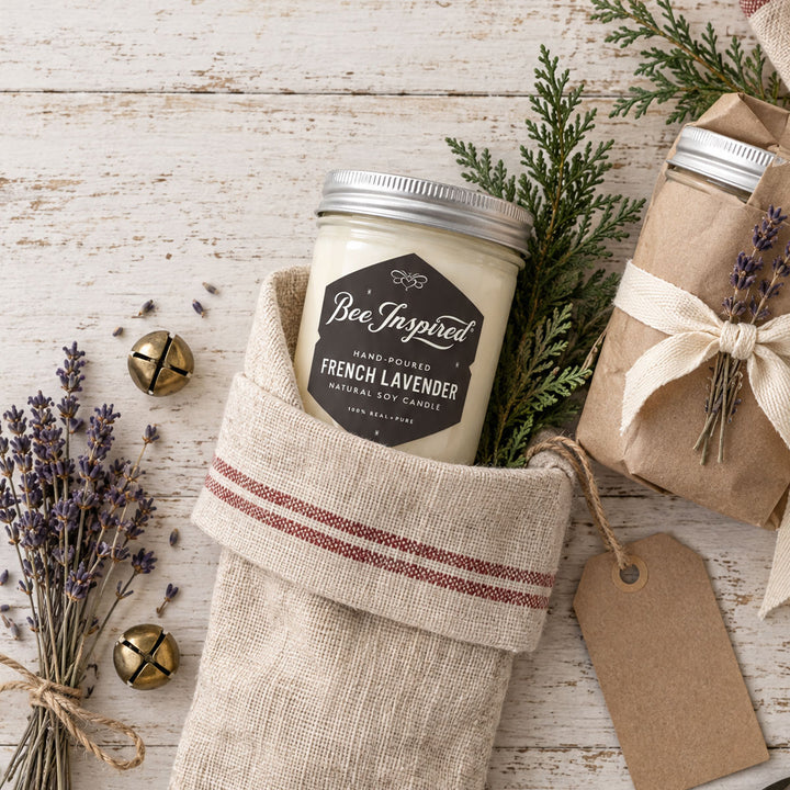 bee inspired french lavender candle in linen holiday stocking with jingle bells and a candle wrapped in kraft paper and holiday greenery and dried lavender