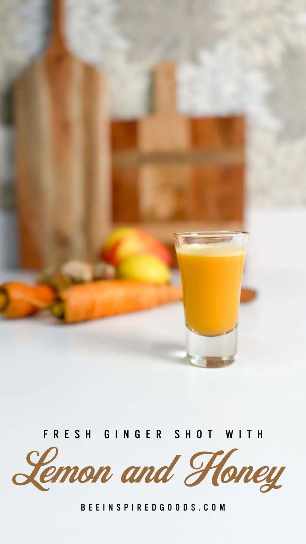 Shot glass of fresh ginger juice with carrots and a cutting board in the background, featuring text about the drink and brand.