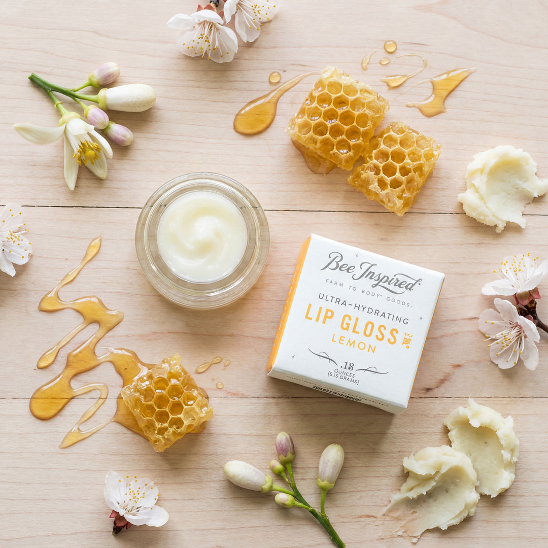 Lip gloss with honeycomb and flowers on a wooden surface