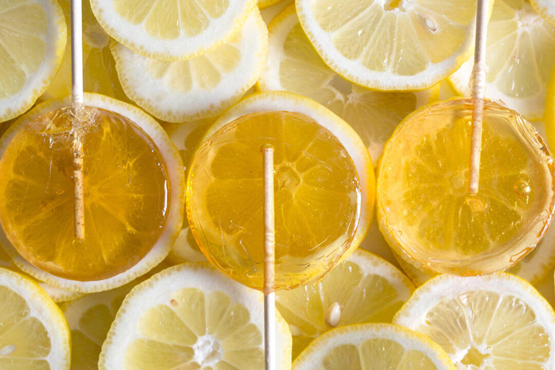 Bee Inspired lemon honey lollipops against lemon slices 