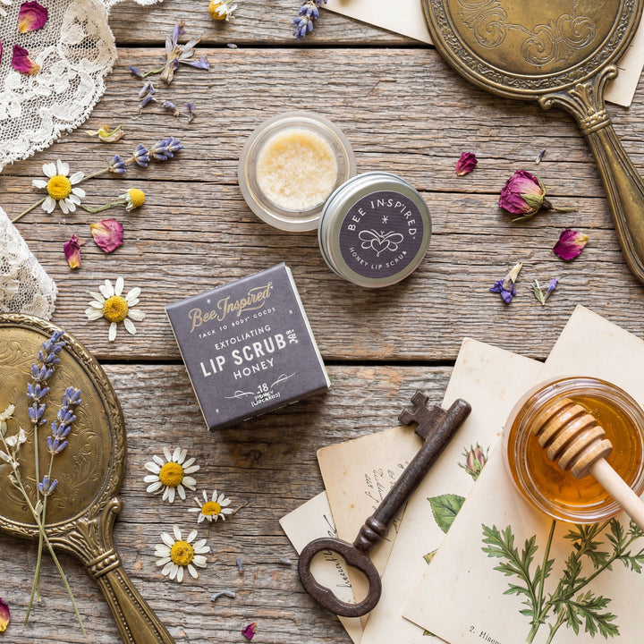 Lip scrub with packaging on a rustic wooden surface with flowers and honey.