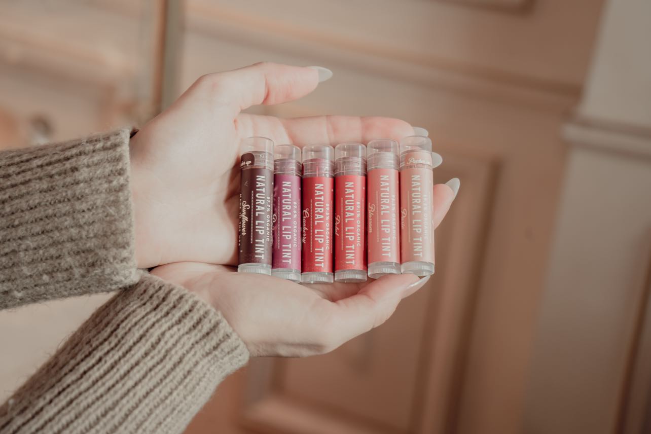 A person holding six Bee Inspired lip tints in different shades 