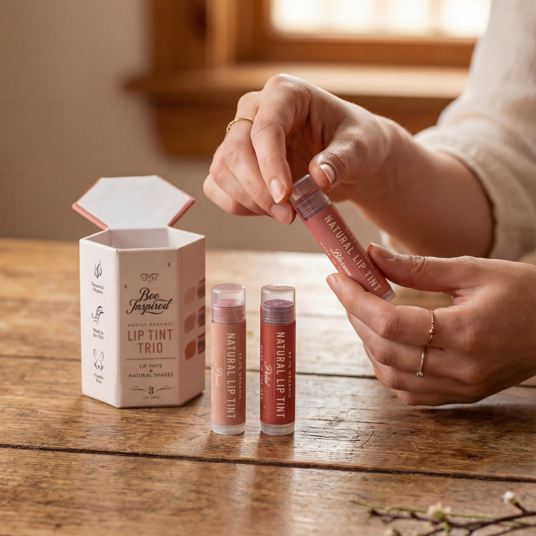 Person holding a lip tint with a set of lip tint tubes and packaging on a wooden surface.