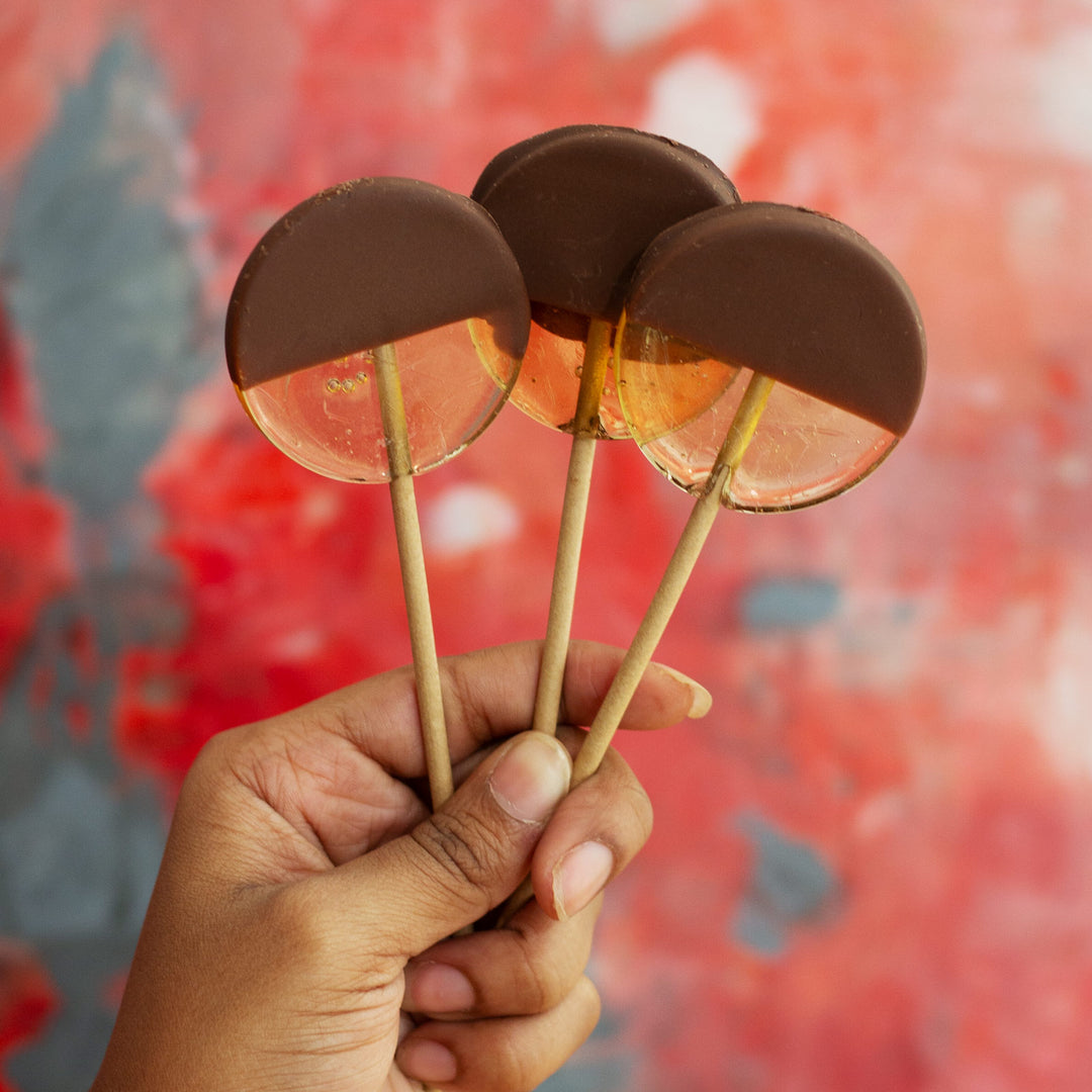 Hand holding chocolate-dipped lollipops 