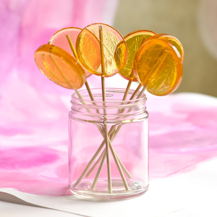 Lollipop display in glass jar against pink art 