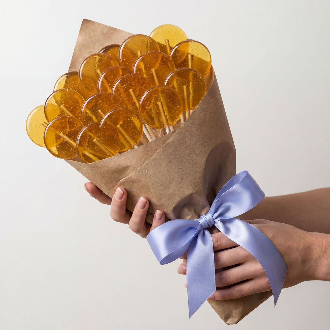 Bouquet of yellow lollipops wrapped in brown paper with a blue ribbon held by hands against a light background