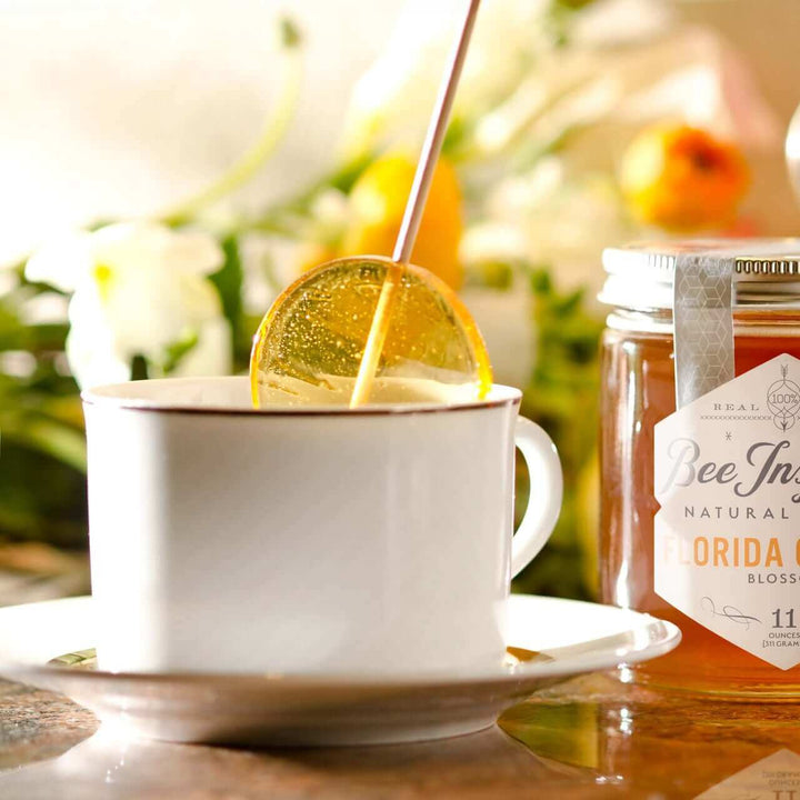 Florida Orange honey by Bee Inspired Goods with a white tea cup and a honey lollipop