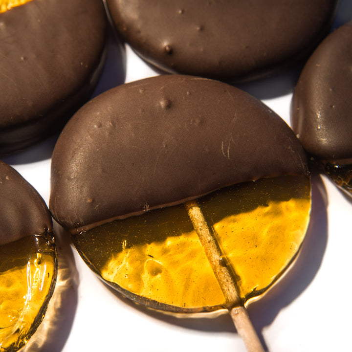 Close-up of chocolate-covered lollipops on a white surface
