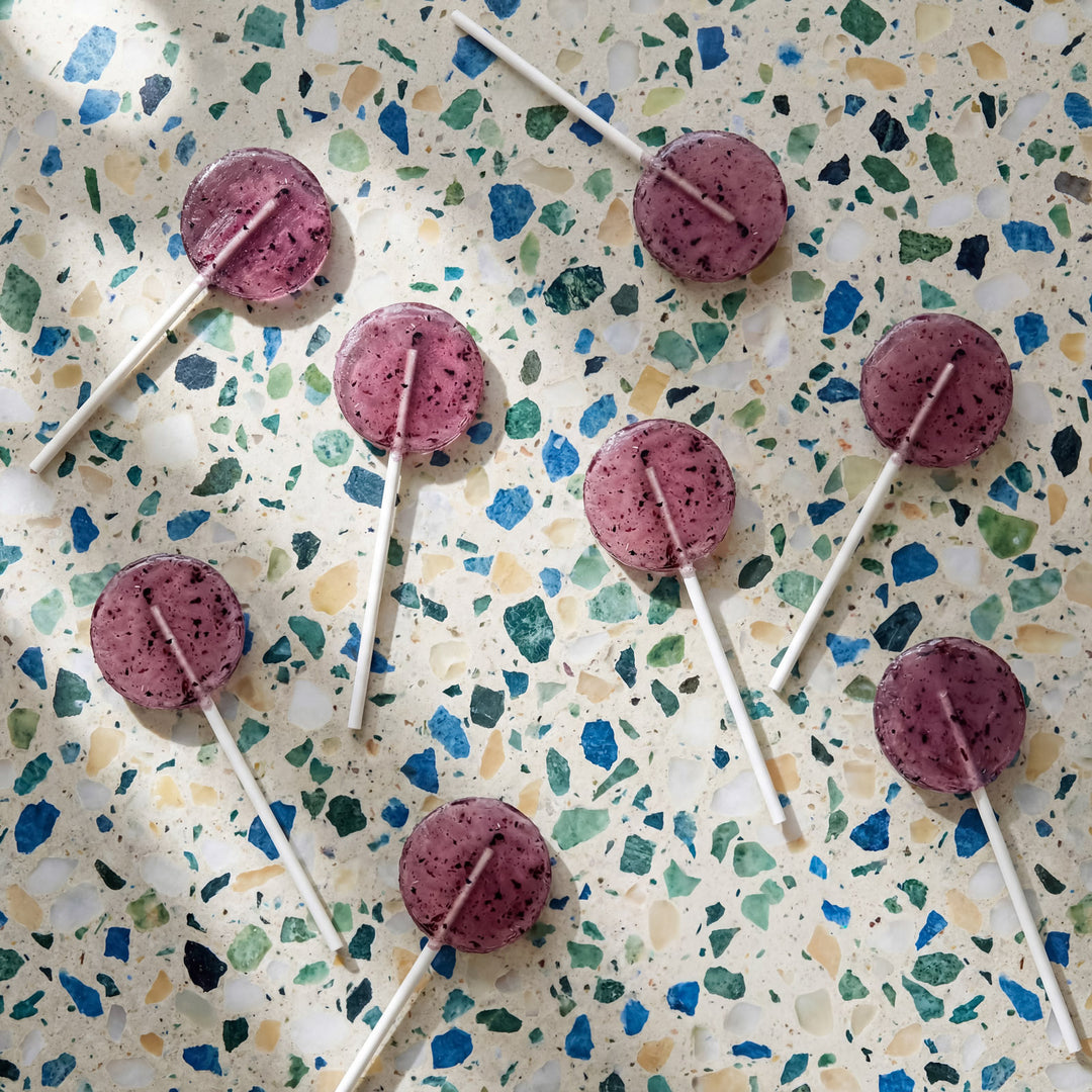 Purple berry lollipops on a speckled surface