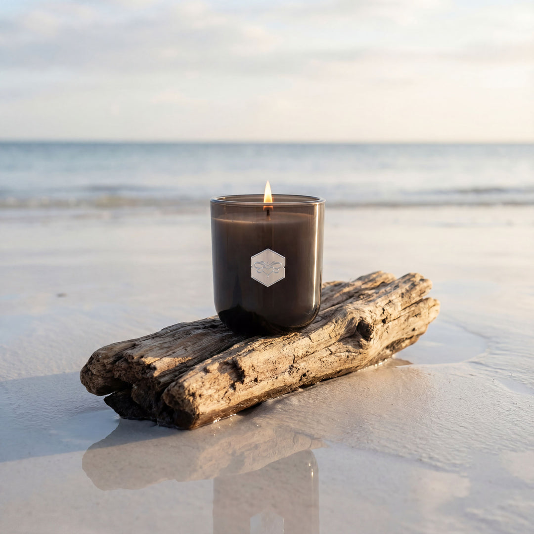 Black candle with a label on a piece of driftwood on a beach