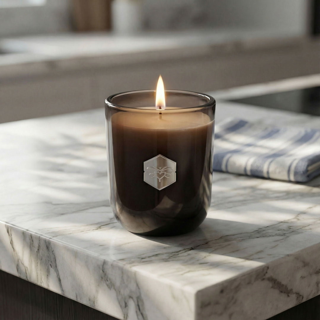 Candle in a glass holder with a logo on a marble surface