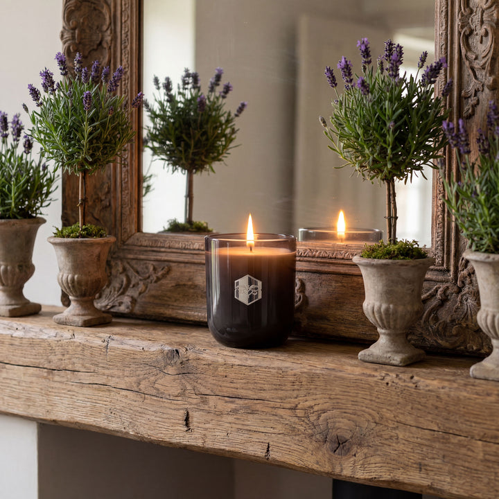 Candle with a logo on a wooden surface with decorative elements and plants.