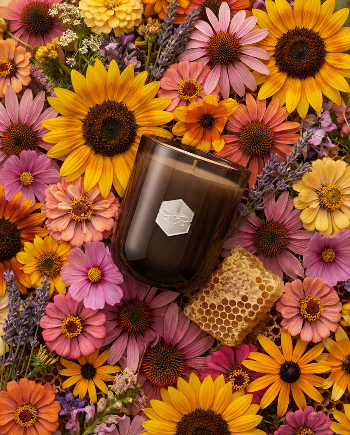 Candle with a honeycomb surrounded by colorful flowers