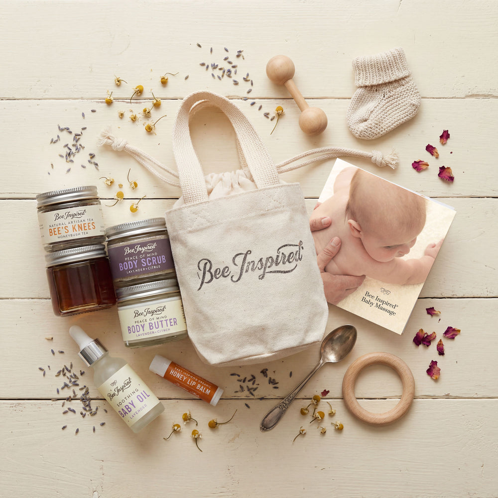 Baby care products and 'Bee Inspired' tote bag on a wooden surface with baby items.