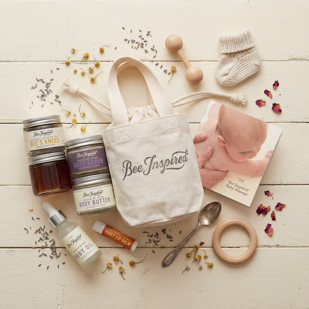 Baby care products and 'Bee Inspired' tote bag on a wooden surface with baby items.