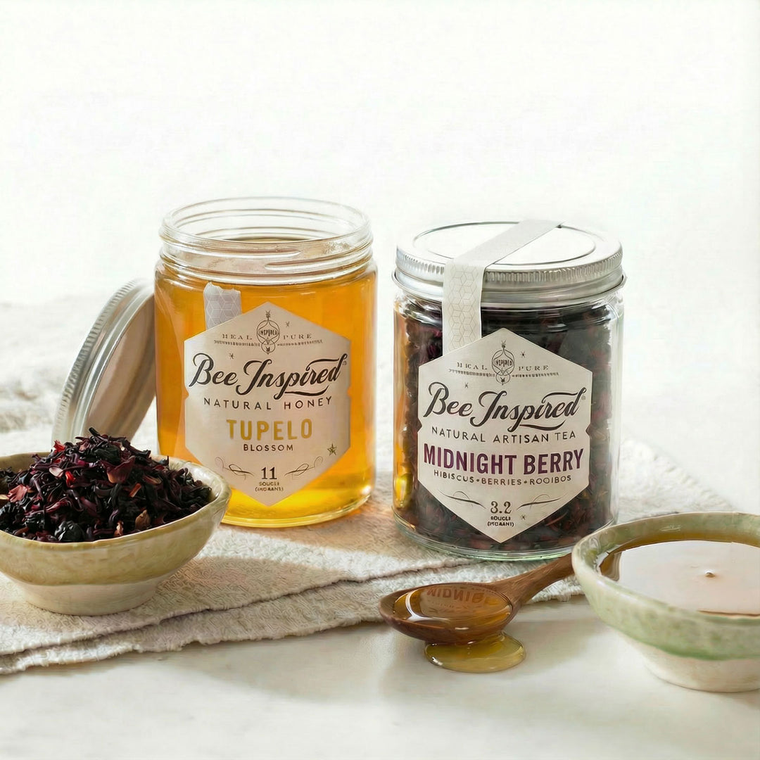 Two jars of 'Bee Inspired' honey and tea on a white surface with a spoon and small bowls.