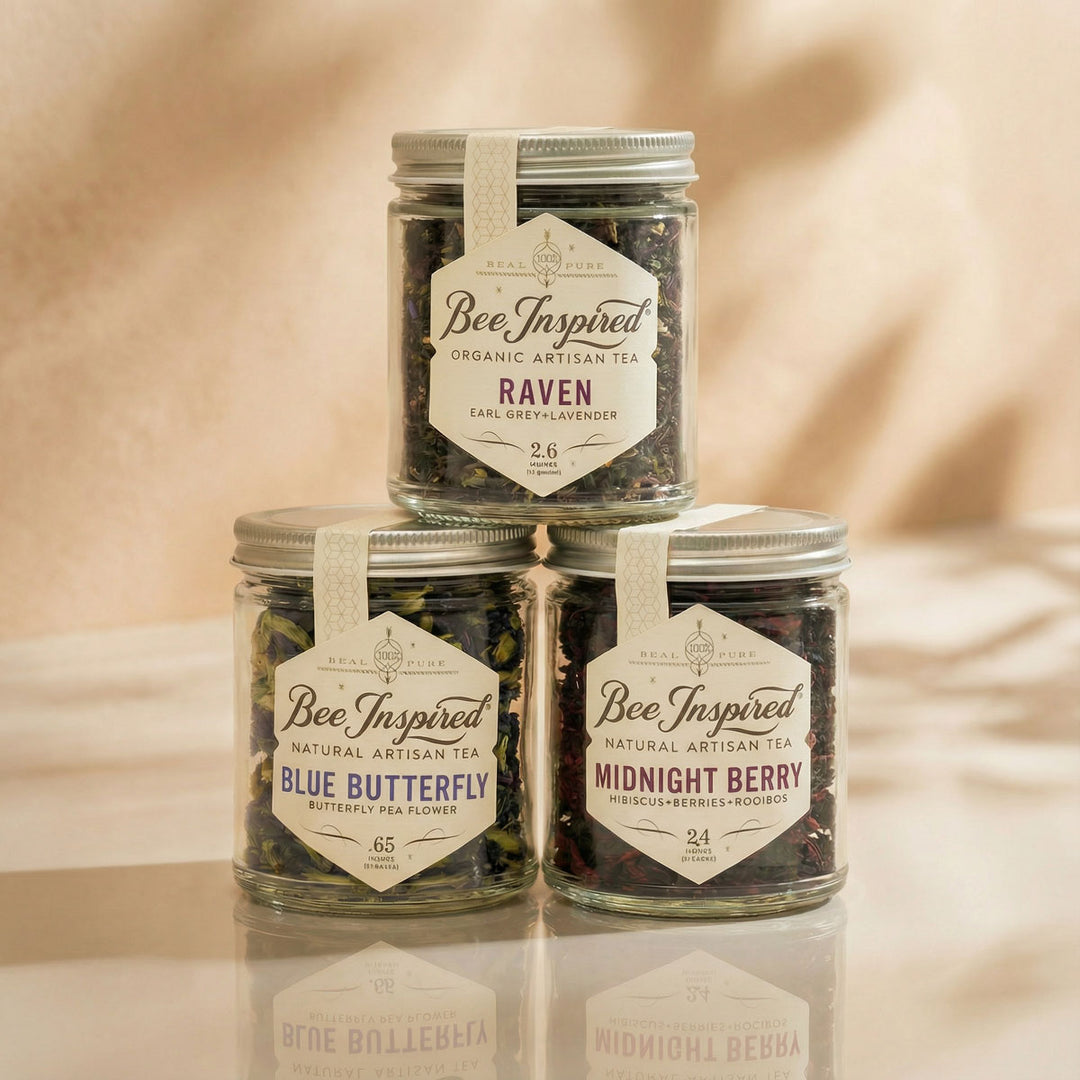 Three jars of 'Bee Inspired' organic artisan tea on a beige fabric background
