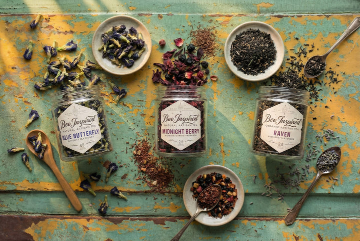 Jars of Bee Inspired tea with dried herbs on a rustic wooden surface