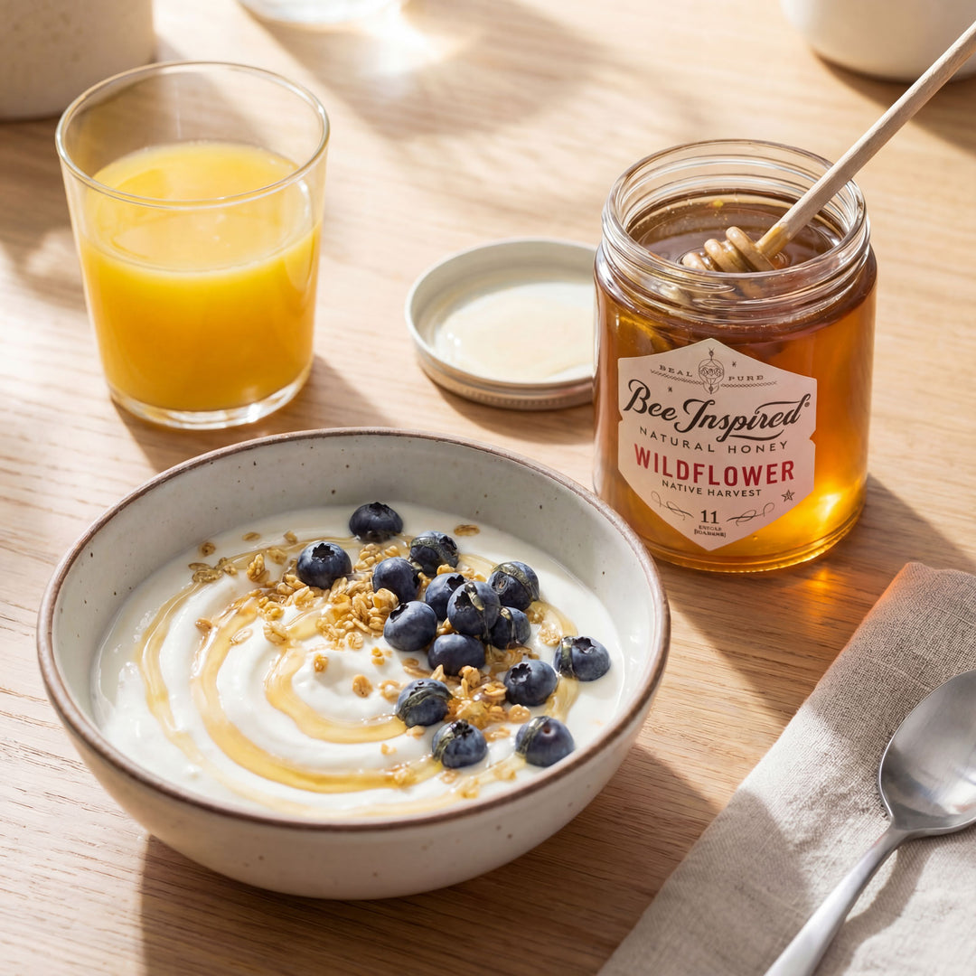 Yogurt bowl with blueberries, a jar of honey, and a glass of orange juice on a wooden table.