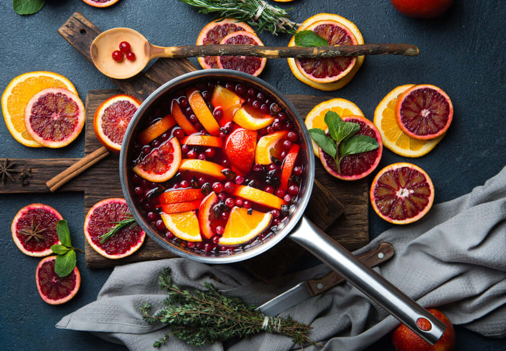 mulled wind in a stove pot topped and surrounded with berries and citrus fruits