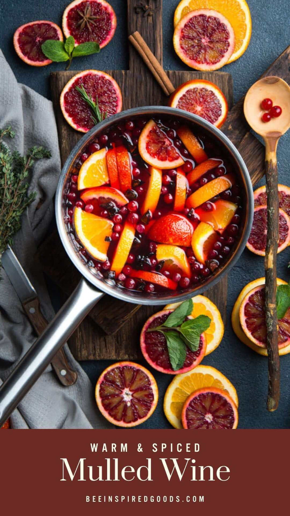 "Warm & spiced mulled wine beeinspiredgoods.com" with a pot full of cranberries and orange slices 