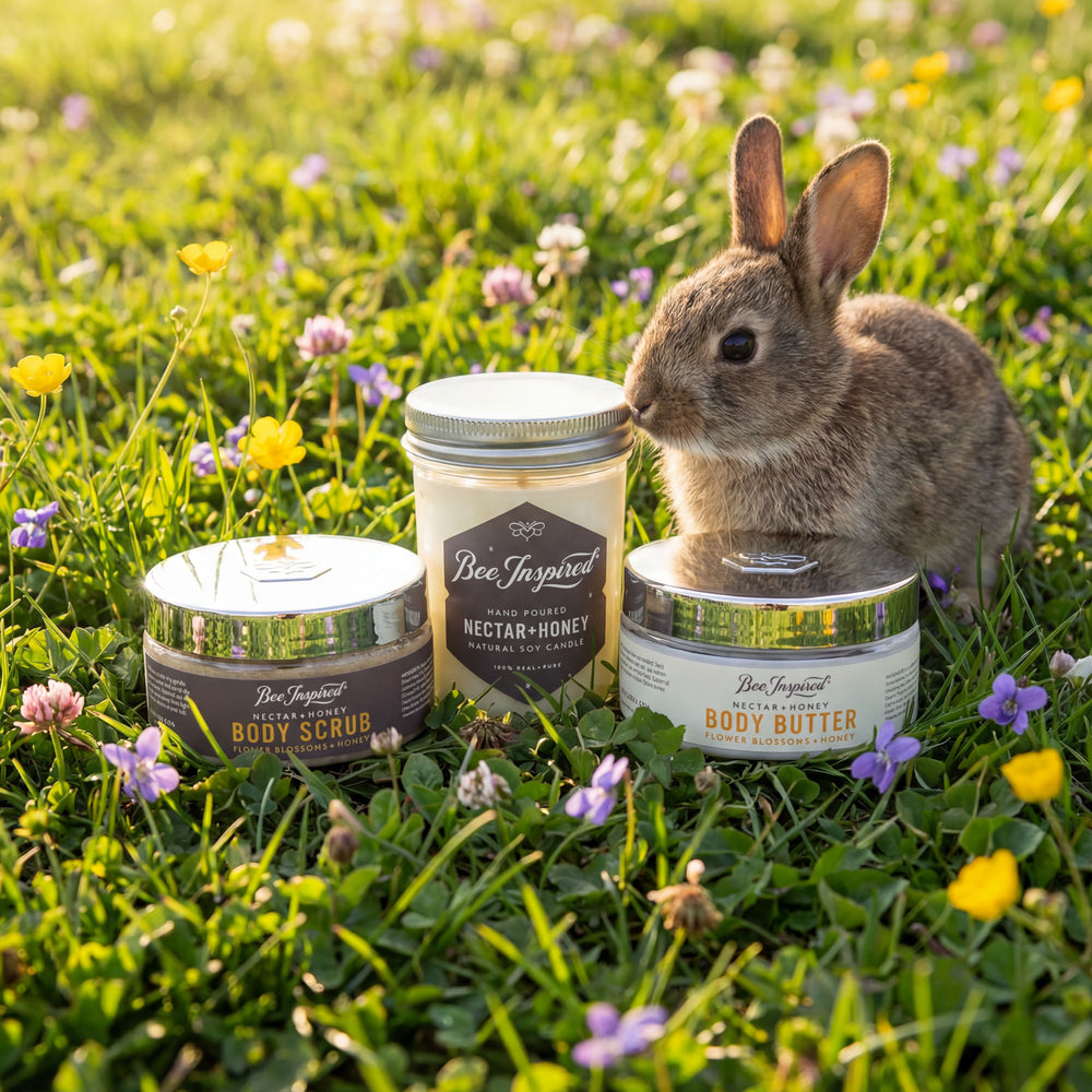 Three containers of 'Bee Inspired' products on a grassy field with a rabbit.