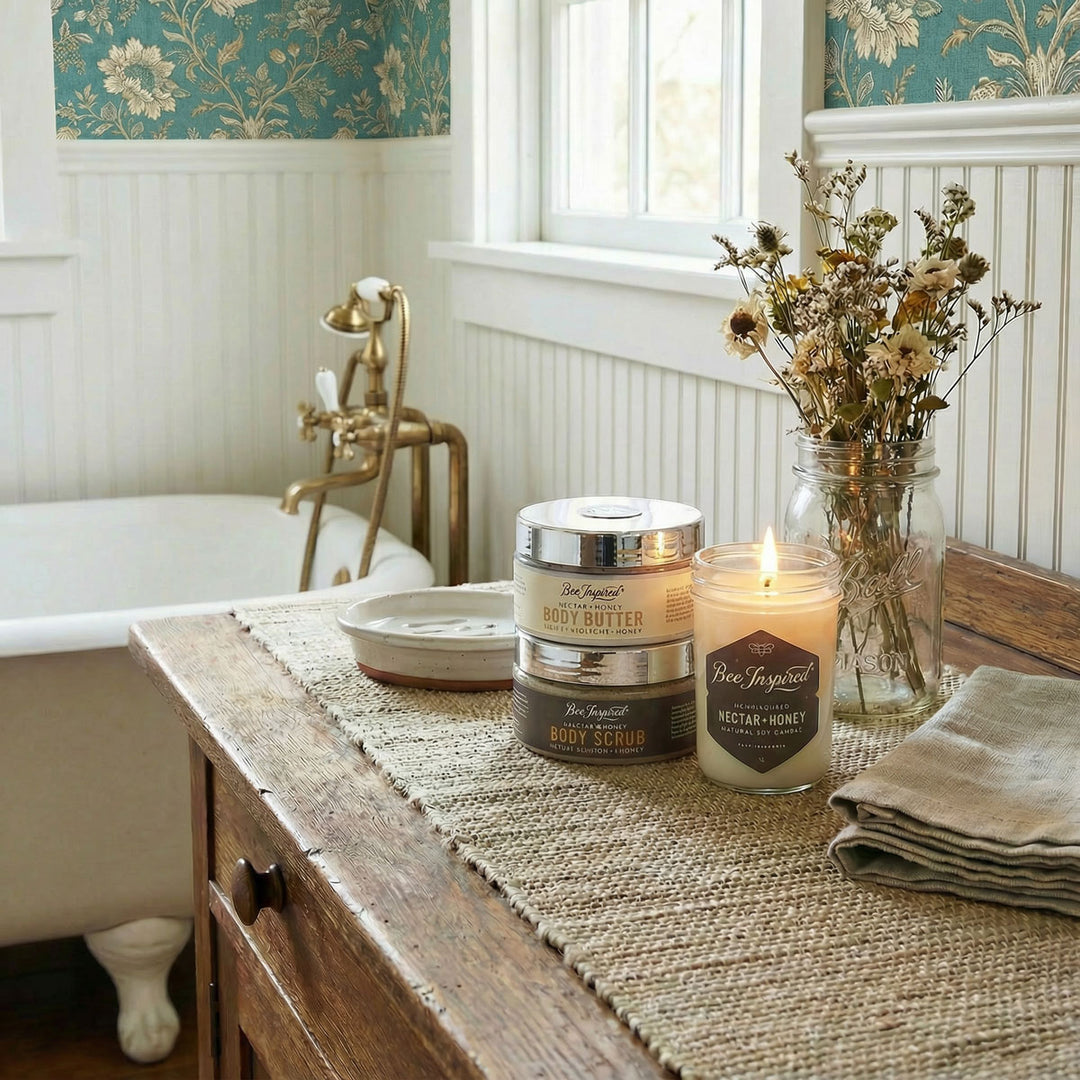 Candle and body care products on a wooden table with floral wallpaper in the background