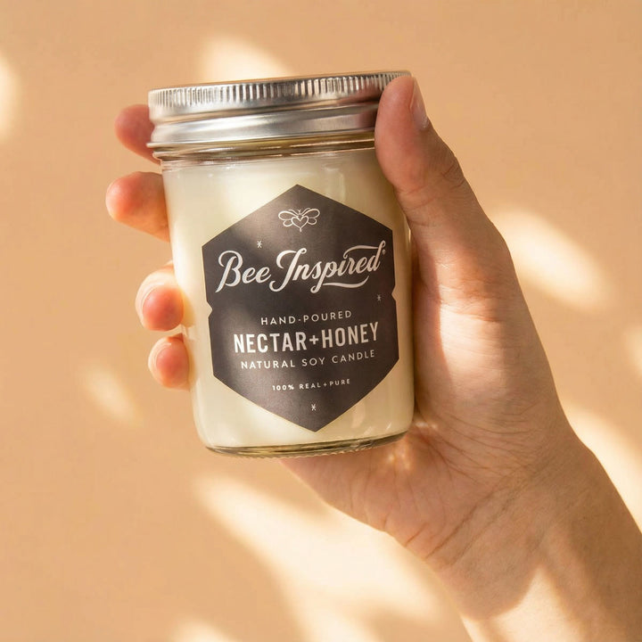 Hand holding Bee Inspired nectar honey candle against a beige background