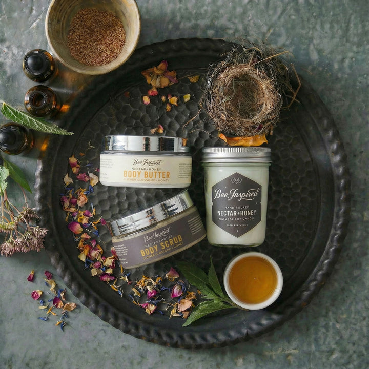 Bee-Inspired natural body care products on a textured surface with herbs and honey.