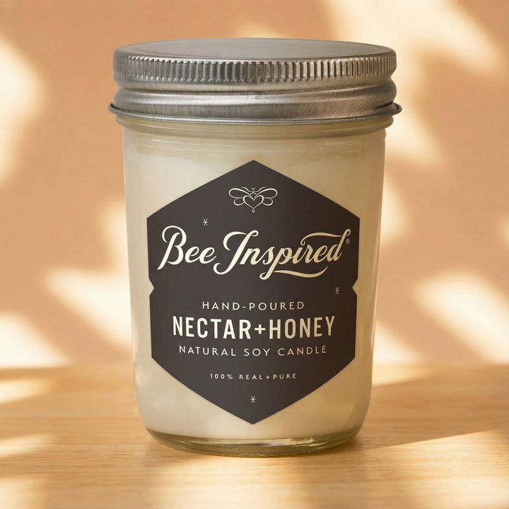 Bee Inspired nectar honey candle in a glass jar with a metal lid on a light dappledd surface