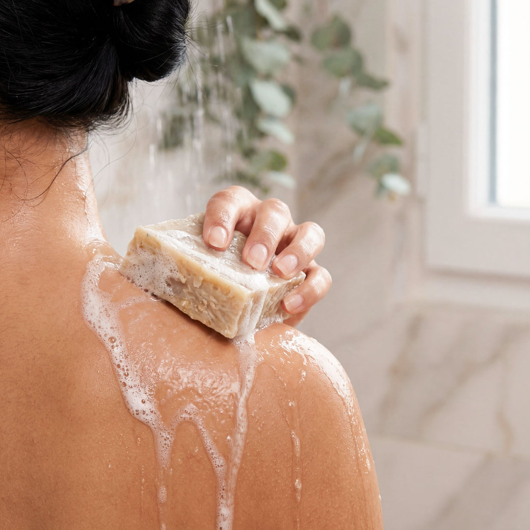 Person scrubbing their back with a bar of soap in a bathroom setting