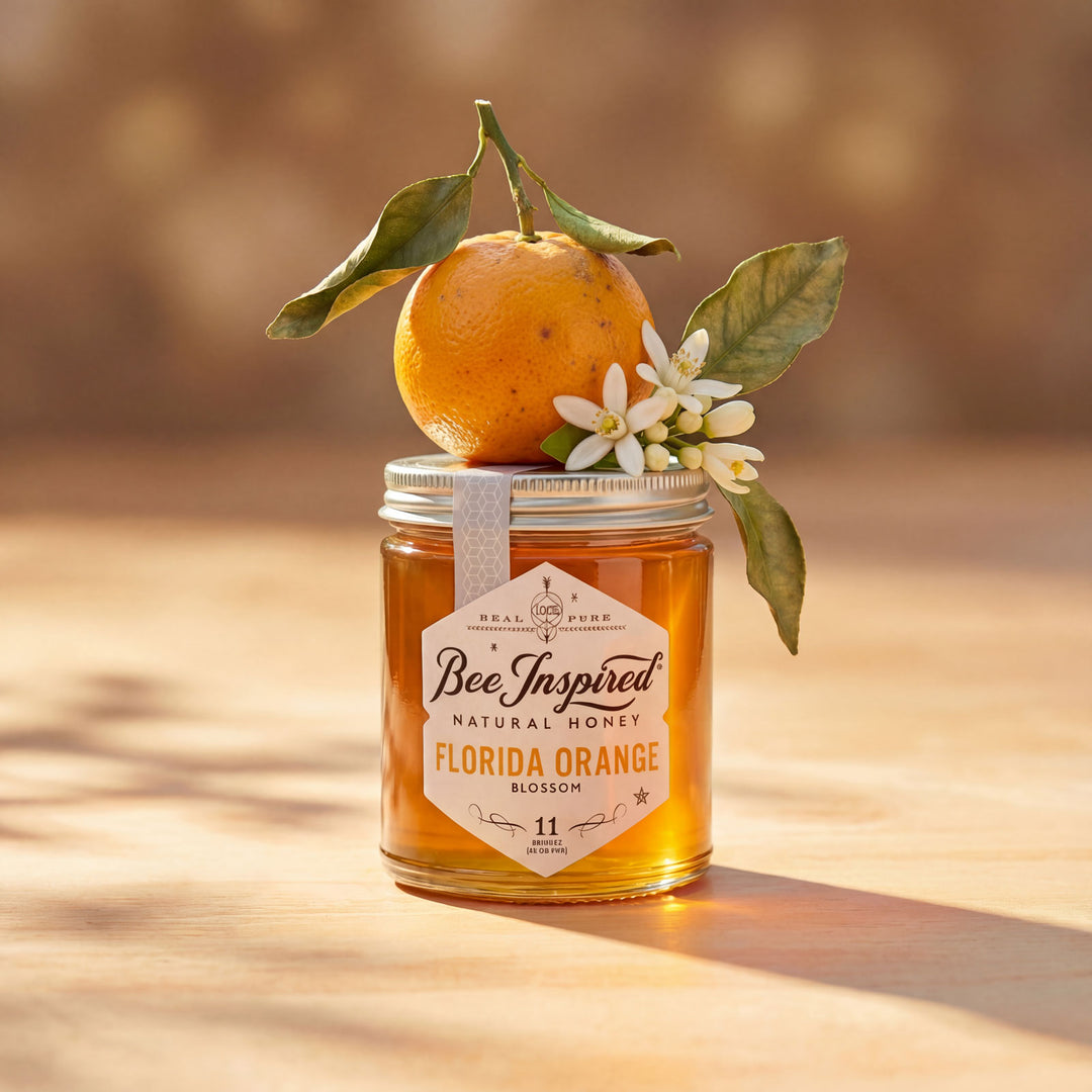 Jar of 'Bee Inspired' Florida Orange Blossom honey with an orange and flowers on a wooden surface.