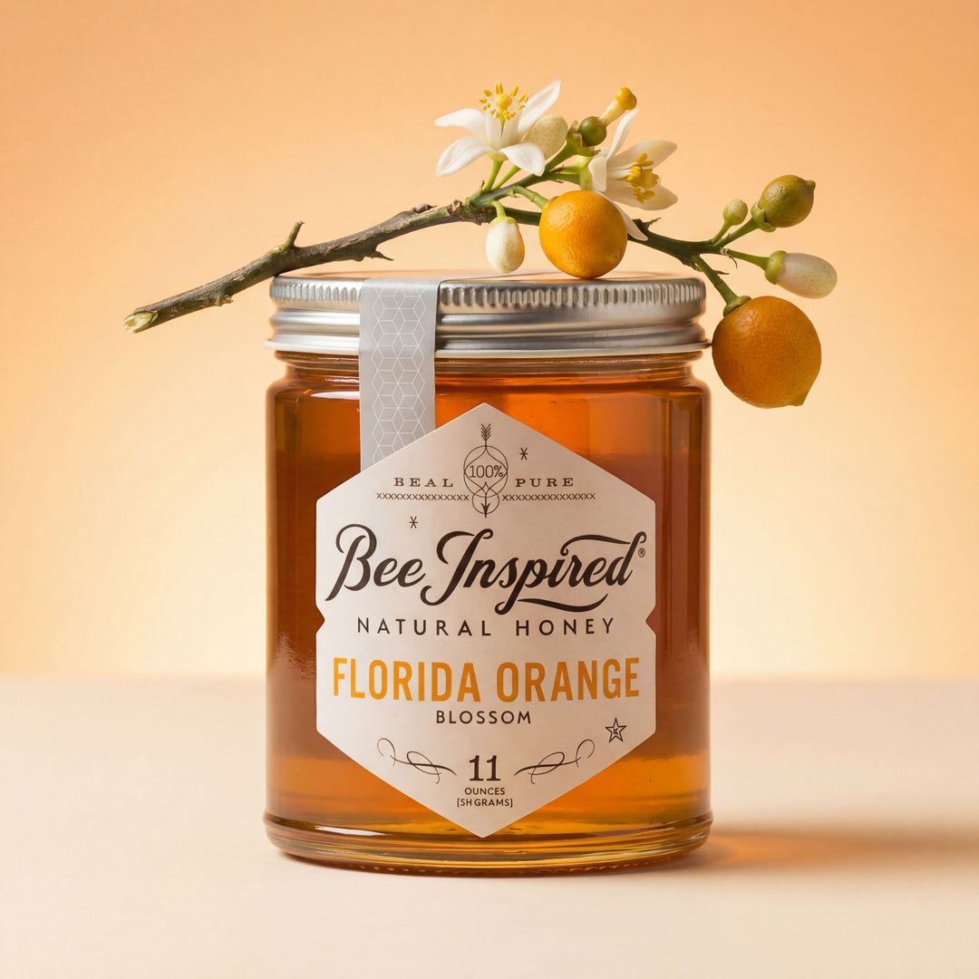 Jar of Bee Inspired Natural Honey with a branch of oranges and flowers on an orange background