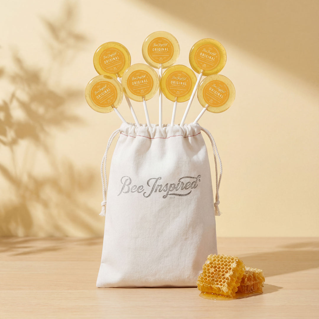 Set of honeycomb-shaped lollipops with a 'Bee Inspired' drawstring bag on a beige background