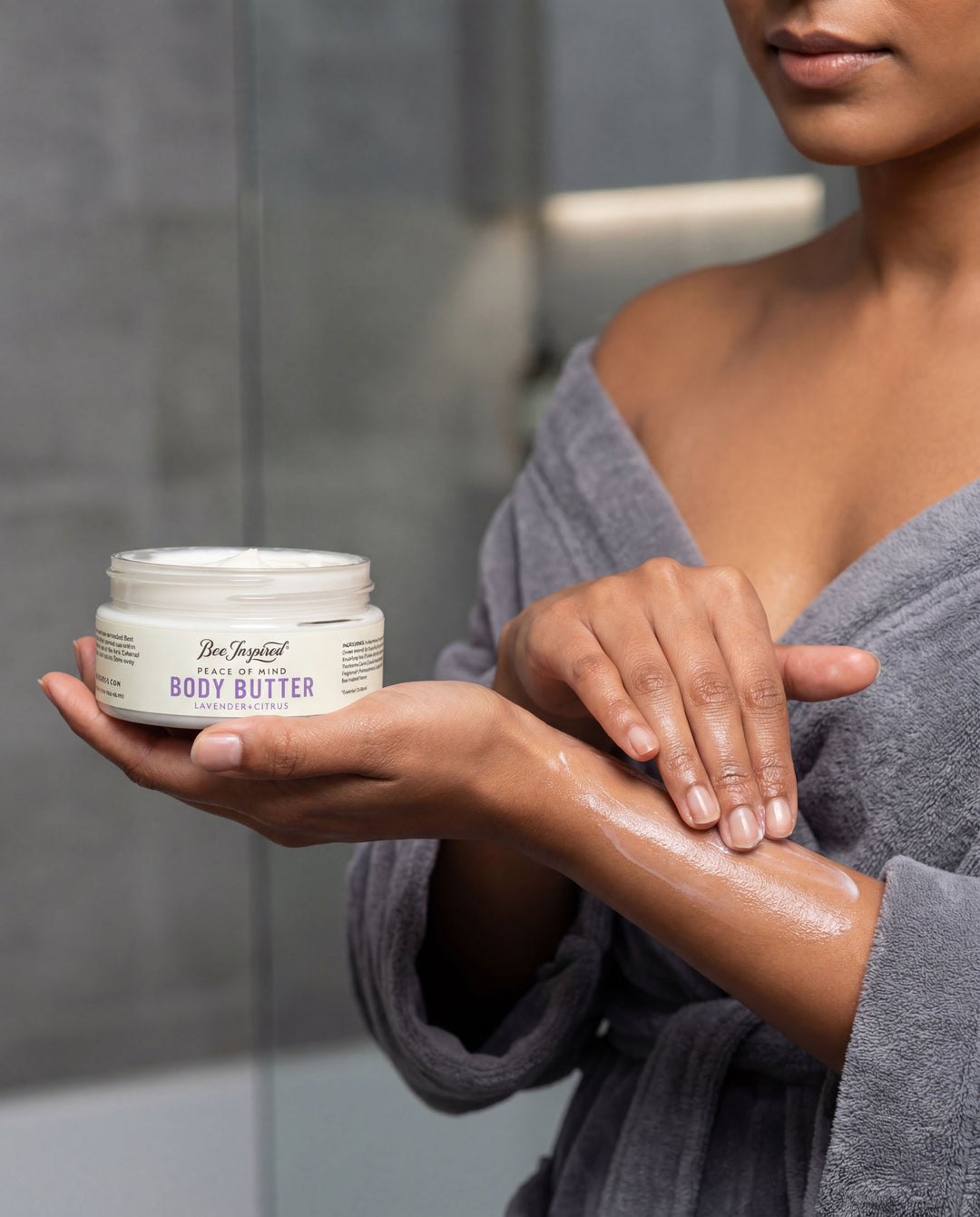 Person applying body butter to their hand in a bathroom setting