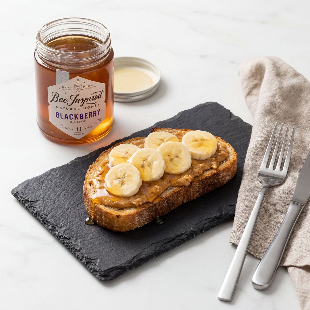 Toast with banana slices, peanut butter, and honey on a slate board with Bee Inspired honey jar.