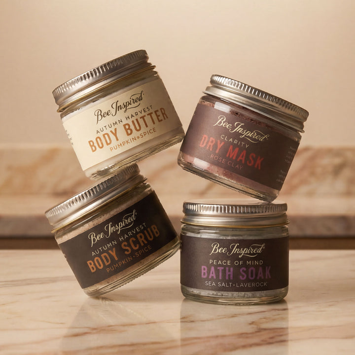 Four jars of Bee Inspired body care products on a wooden surface.