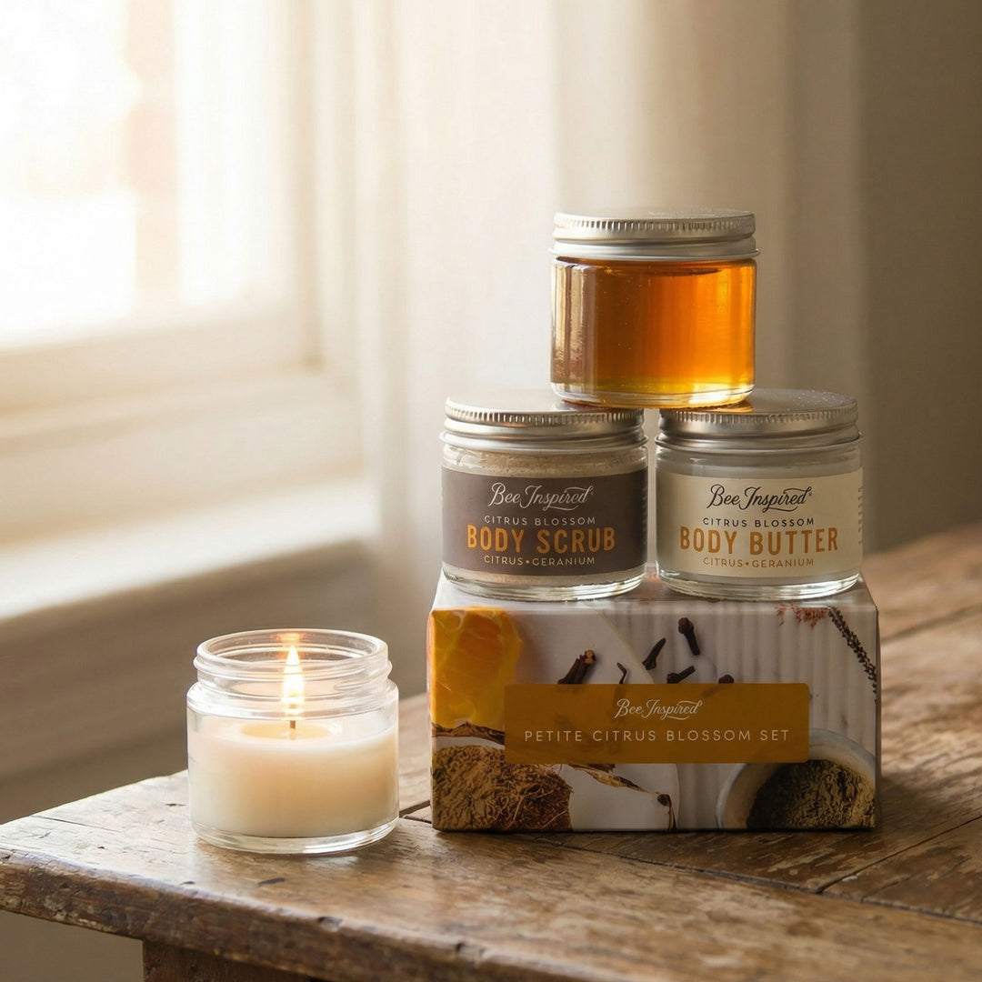 Set of body care products including a candle, jars, and a box on a wooden surface.