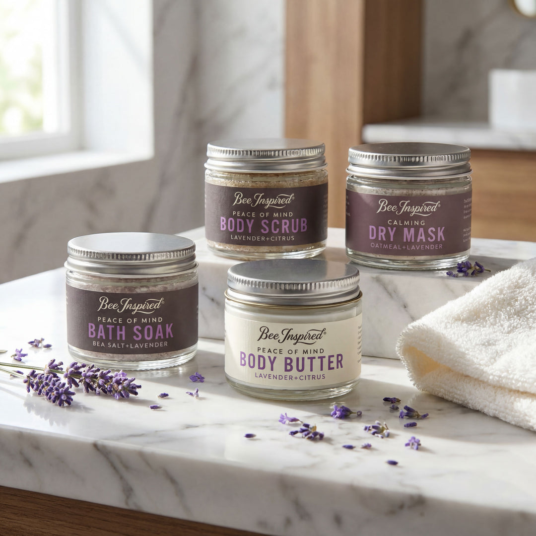 Set of Bee Inspired skincare products on a marble surface with lavender flowers.