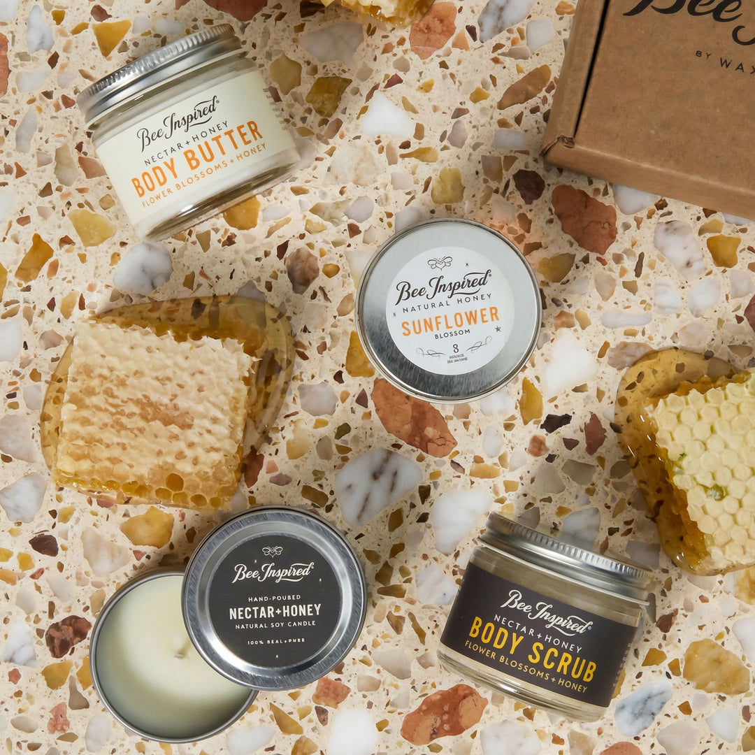 Collection of Bee Inspired body care products on a textured surface with honeycomb and beeswax elements.