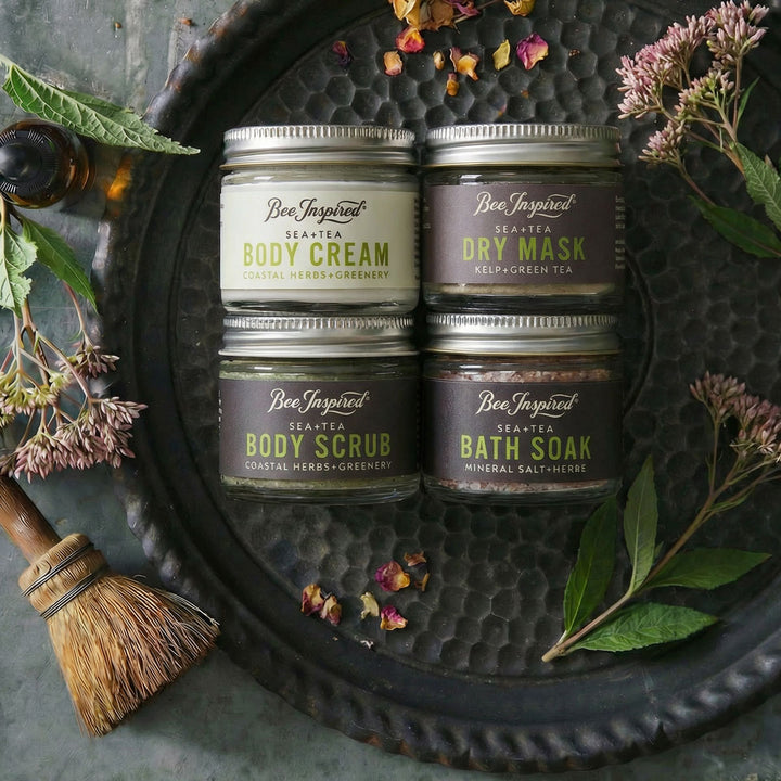 Set of Bee Inspired skincare products on a dark textured surface with natural elements.